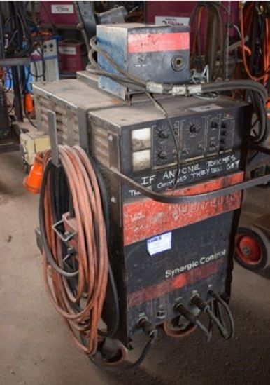 A well used CIG Transmig 350 Pulse in a workshop with a handwritten warning above the control panel
